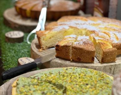 Dolci vari su tavoli di legno, inclusa torta al pistacchio.