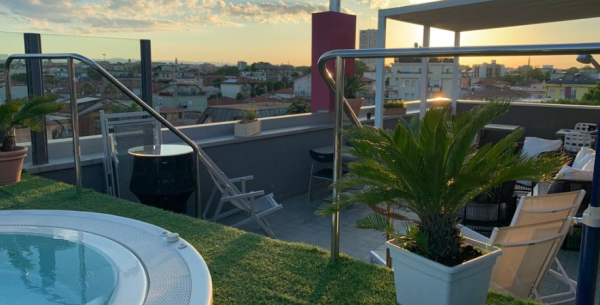 Terrazza con jacuzzi, piante e vista al tramonto.